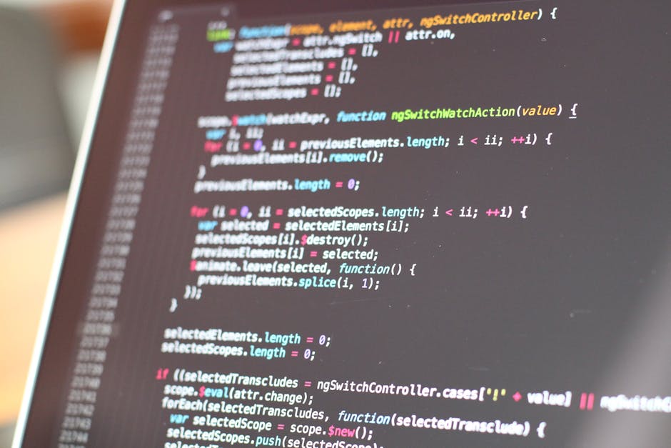 A close-up photograph of a computer screen displaying lines of colourful programming code, including keywords, functions, and syntax elements in various colours such as red, green, blue, yellow, and w
